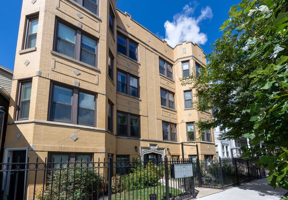 Front view of a multi-story apartment building with a yellow brick facade.