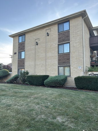 Front view of a multi-story brick building with multiple windows.