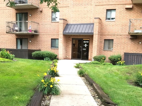 Front view of a multi-story brick apartment building with balconies.