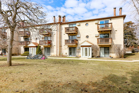 Front view of a three-story apartment building with balconies and multiple entrances.
