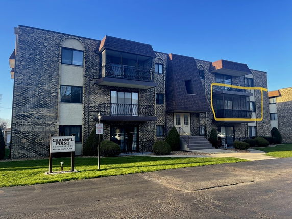 Front view of a multi-story condominium building with brick facade and balconies.