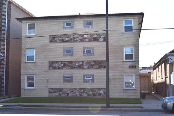 Front view of a three-story apartment building with brick and stone facade.
