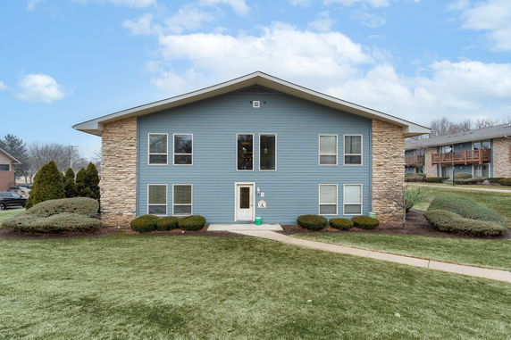 Front view of a two-story building with blue siding and stone accents.