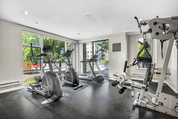 Indoor gym area with exercise equipment and large windows.
