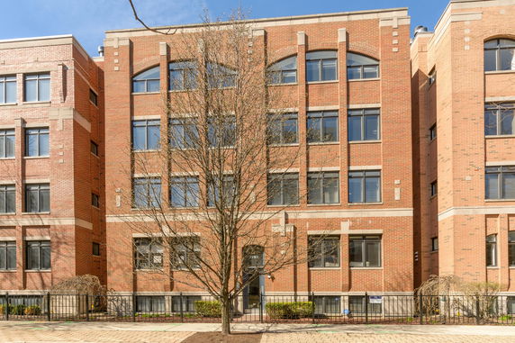 Front view of a multi-story brick building with large windows.
