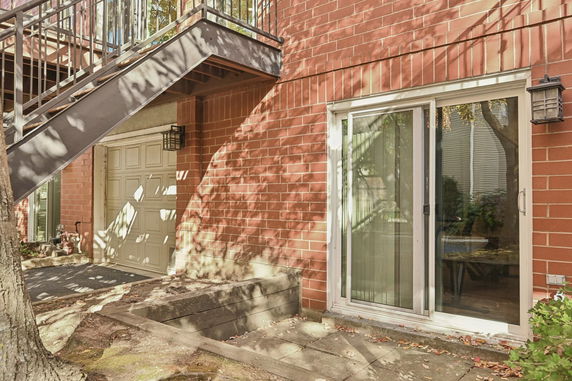 Exterior view of a brick building with a garage door and a sliding glass door.