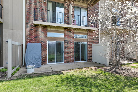 Rear view of a two-story brick building with balconies and sliding glass doors.