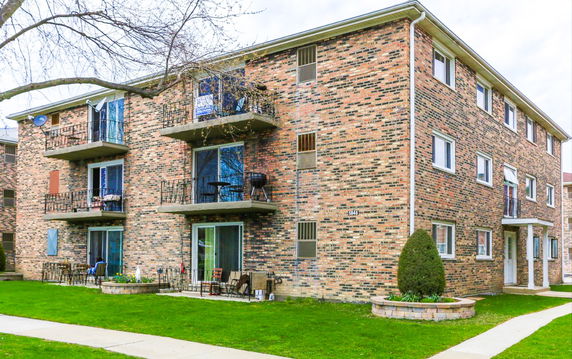 Front view of a three-story brick apartment building with balconies.