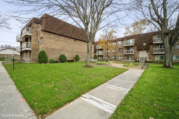 Front view of a multi-story brick apartment building with balconies.
