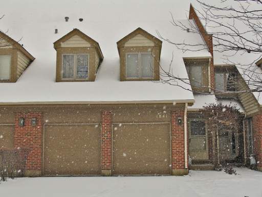 Front view of a house with a snow-covered roof and two-car garage.