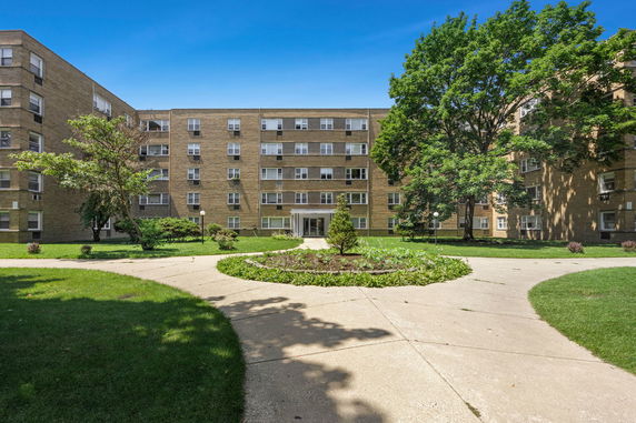 Front view of a multi-story residential building with a central walkway leading to the entrance.