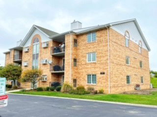Front view of a multi-story brick building with multiple balconies and pitched roof.