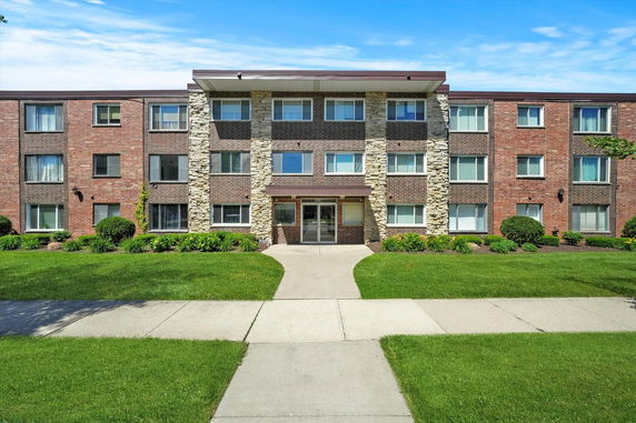 Front view of a multi-story brick apartment building with a central entrance.
