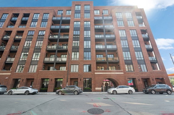 Front view of a multi-story brick apartment building with balconies.