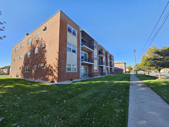 Front view of a multi-story brick apartment building with balconies.