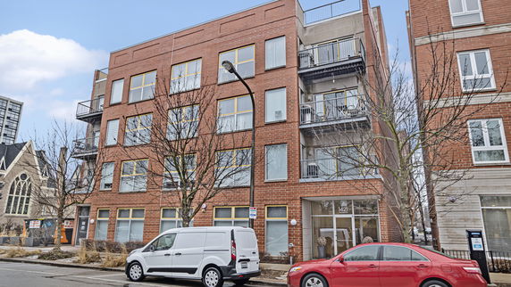 Front view of a multi-story brick apartment building with balconies.