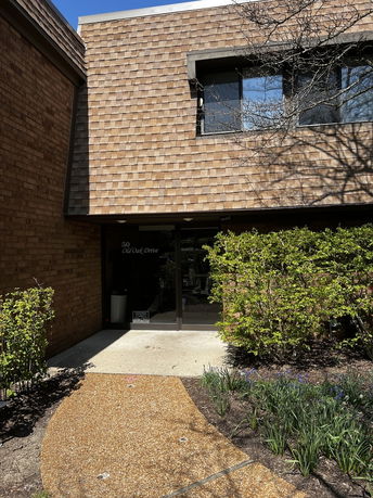 Front view of a building with a shingle facade and a glass entrance door.