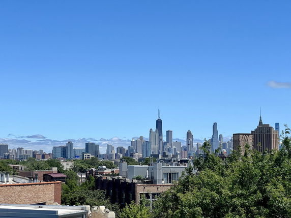 Panoramic view of a city skyline with multiple skyscrapers under a clear blue sky.