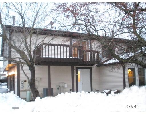 Front view of a two-story house with a balcony and snow around the base.