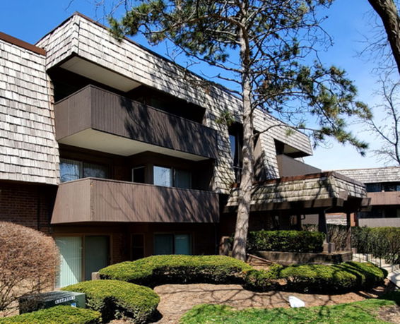 Front view of a multi-story residential building with balconies and wood paneling.