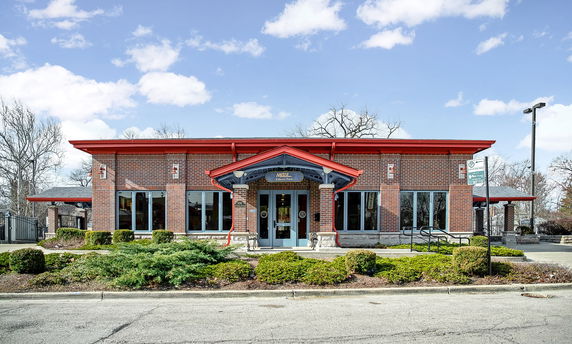 Front view of a single-story building with red accents and large windows.
