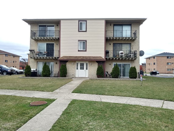Front view of a three-story apartment building with balconies on each floor.
