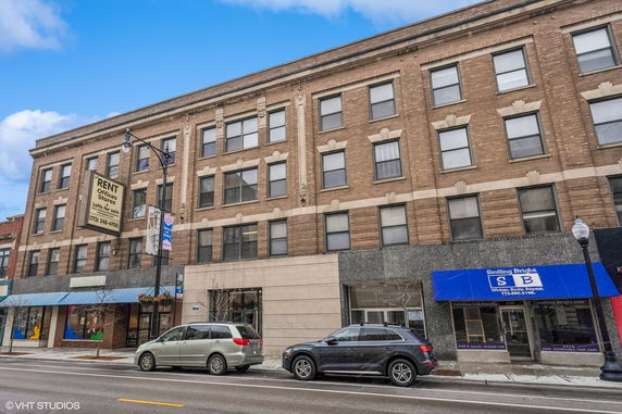 Front view of a multi-story brick building with storefronts and office spaces for rent.