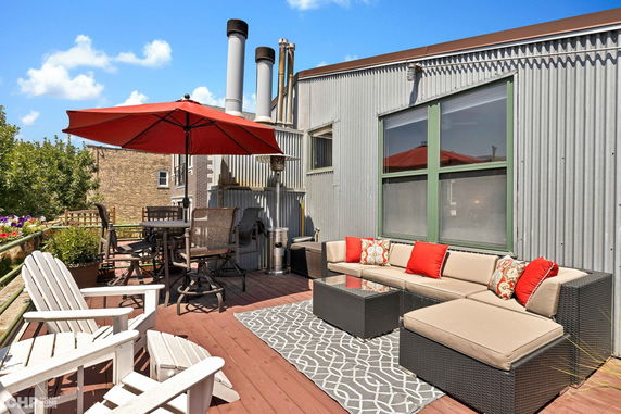 Rooftop with seating area and patio furniture under a red umbrella.