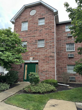 Front view of a multi-story brick building with green entrance door.