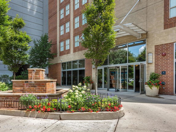 Front view of a multi-story building with a glass entrance and a brick facade.