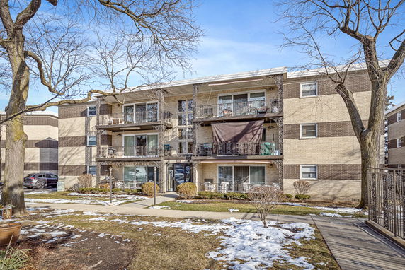 Front view of a three-story apartment building with balconies and brick exterior.