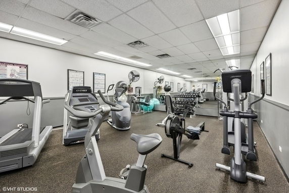 Room with various gym equipment including treadmills, elliptical machines, and dumbbells.