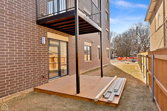 Side view of a brick building with a balcony and a wooden deck.