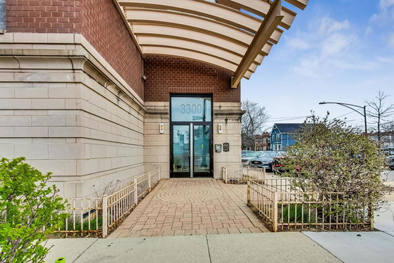 Front view of a brick building entrance with glass doors.