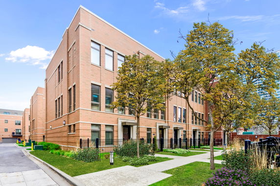 Front view of a multi-story brick building with large windows and multiple entrances.