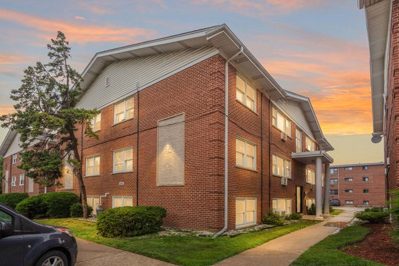 Front view of a two-story brick apartment building with multiple windows.