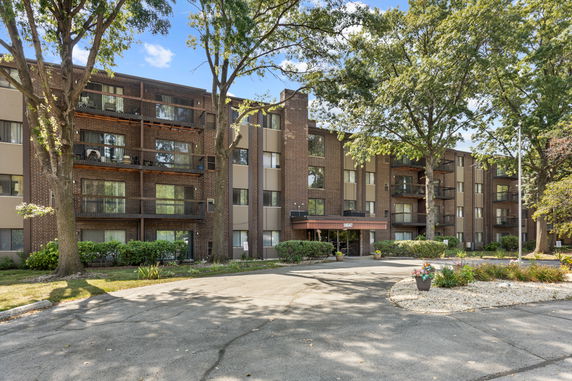 Front view of a multi-story apartment building with balconies and brick facade.