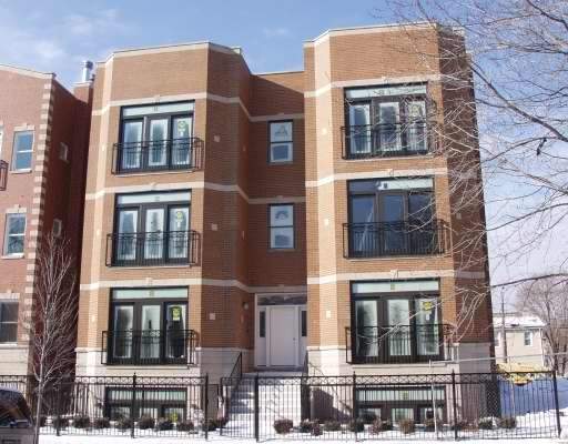 Front view of a three-story brick building with balconies.