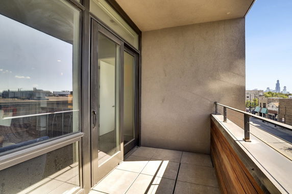 Small rooftop balcony with glass door and metal railing.