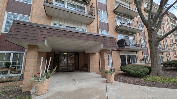 Front view of a multi-story building with balconies and entrance canopy.