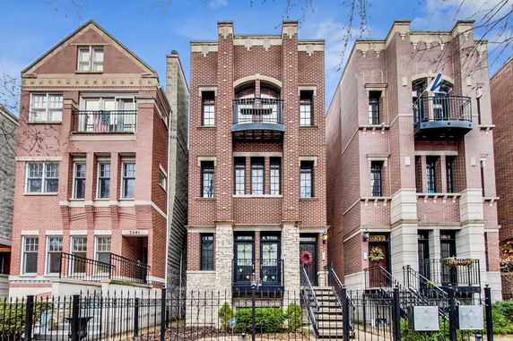 Front view of brick townhouses with balconies and decorative arches.
