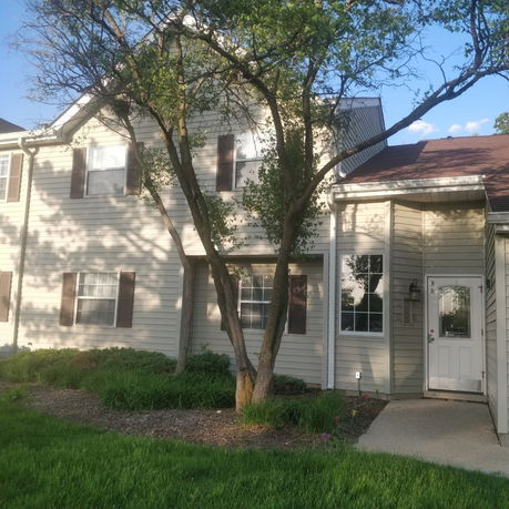 Front view of a two-story house with white siding and brown shutters.