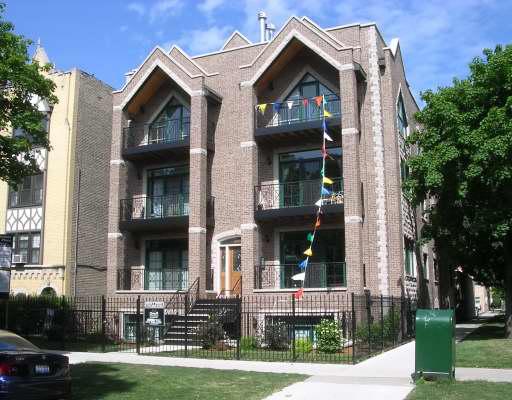 Front view of a multi-story brick building with balconies and decorative flags.