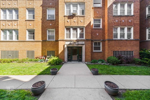 Front view of a brick apartment building with multiple windows.