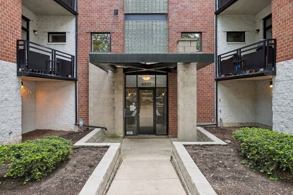 Front view of a multi-story building entrance with brick and concrete facade.