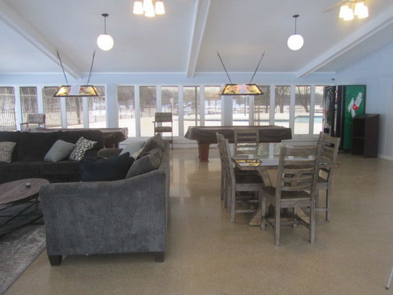 Room with pool tables, seating area, and dining table for recreation activities.