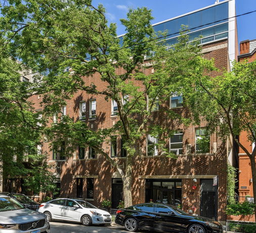 Front view of a multi-story brick building with trees in front.