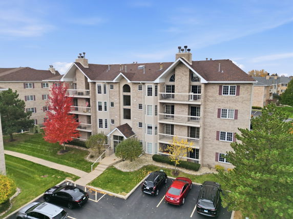 Front view of a multi-story apartment building with balconies and gable roofs.