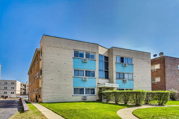 Front view of a multi-story brick apartment building with blue accents and multiple windows.