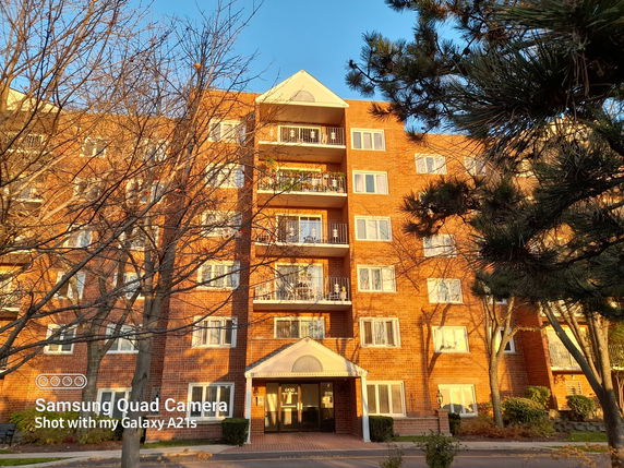 Front view of a multi-story brick apartment building with balconies.